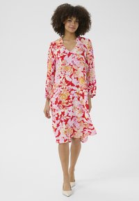 Lillelille kleit, millel on V-kaelus, pikad varrukad ja voolav siluett. Värvid hõlmavad punast, roosat ja kollast ning see on läbipaistva tekstuuriga.