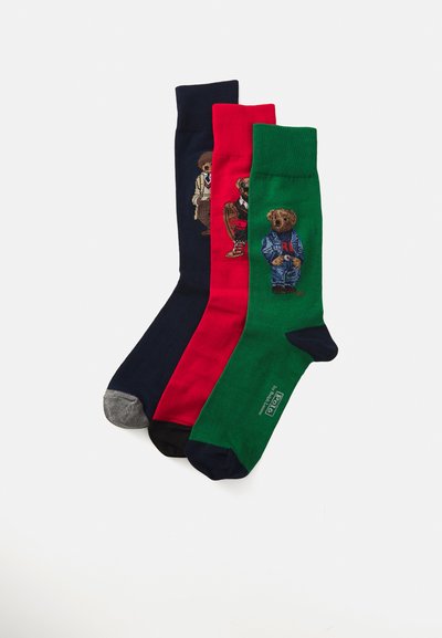 Tre par sokker: marineblå, rød og grønn, hver med broderte bjørnmotiver i forskjellige antrekk; myk stoff, middels lengde.