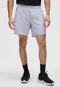 Lichtpaarse sportshorts met een elastische tailleband, zijzakken en een gladde textuur, gecombineerd met zwarte sportschoenen.