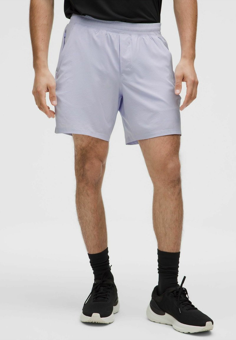 Lichtpaarse sportshorts met een elastische tailleband, zijzakken en een gladde textuur, gecombineerd met zwarte sportschoenen.