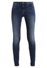 Kape kapeo kaini wa denim buluu ya giza, iliyonayo muundo wa tano wa mifuko wa kawaida, ikionyesha kupungua kidogo kwenye mapaja, na mfuniko wa zipu ulio na kifungo.