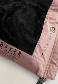 Panno in pile nero bordato da materiale rosa con branding e icone di Ted Baker per resistente all'acqua, durevole, caldo, imbottitura riciclata e polsini antivento.