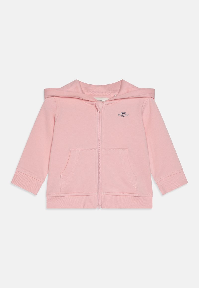 Sweat à capuche zippé rose clair en tissu doux, avec capuche, poches avant et poignets côtelés. Petit logo sur la poitrine gauche.