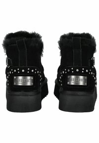 Černé semišové kotníkové boty s umělou kožíškovou podšívkou, stříbrnými cvočky a kovovou logovou destičkou. Ploché gumové podrážky s texturovaným vzorem.