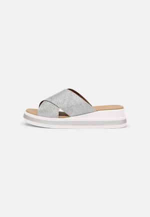 Sandales à brides croisées argentées avec une tige métallique texturée, une semelle intérieure rembourrée et une semelle plateforme blanche pour plus de hauteur.