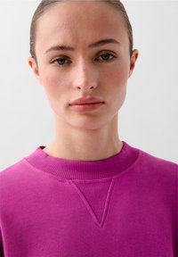 Hanorac fuchsia cu guler rotund din tricot și detaliu texturat în formă de V la guler. Material neted, design ajustat.