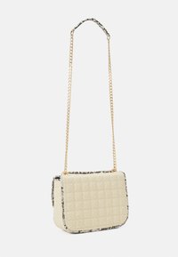 Beige pehmeä laukku, jossa on kultaketjuhihna ja musta-valkoinen kuviointi. Ominaisuuksiin kuuluvat tekstiilikuosi ja läppä suljenta.