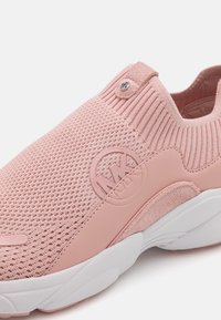 Hele roosa spordijalats, millel on kudumpealne, tekstuuriga viimistlus ja külje peal tõstetud logo detail. Omab valget kummist talla.