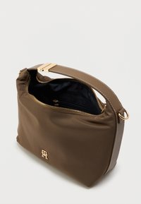 Brun nylonveske med gullbeslag, glidelåslukking og en innerlomme. Har en jevn tekstur og et profilert emblem foran.