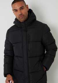 Black puffer jacket with a hood, featuring a front zip closure and zippered chest pocket, quilted design, and elasticated cuffs.