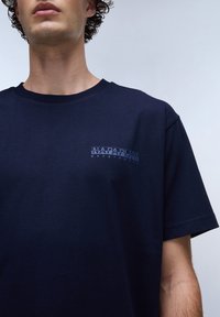 Námořnicky modré tričko s krátkým rukávem z bavlny, s malým světle modrým logem na levé části hrudi. Design s kulatým výstřihem.