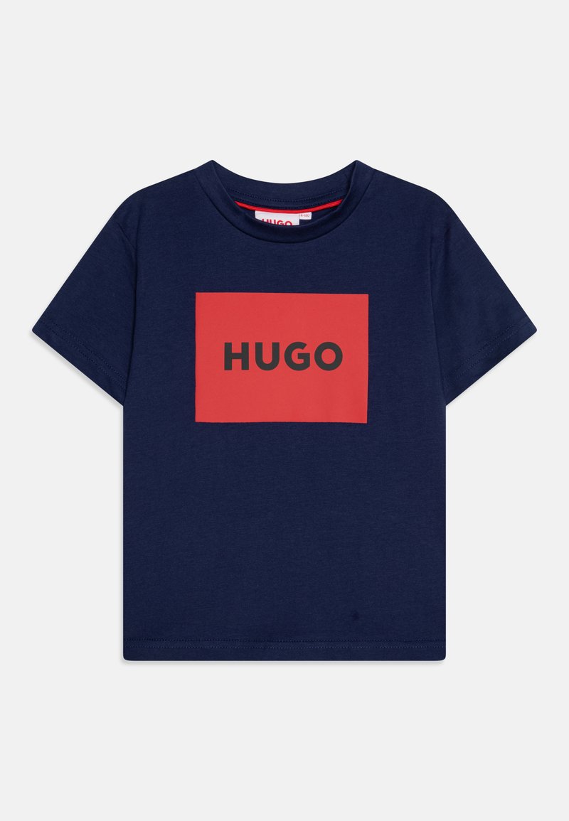 Temno modra bombažna majica z kratkimi rokavi, ki ima rdeč pravokotni grafični vzorec z besedo "HUGO" v debelih črnih črkah in okroglim izrezom.