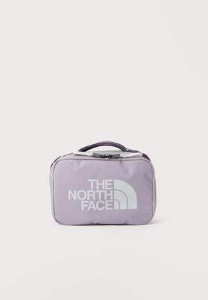 Petit sac rectangulaire violet clair avec poignée et fermeture éclair, marqué d'un grand logo blanc "THE NORTH FACE" sur le devant.
