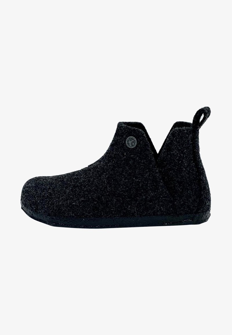 Chausson noir à texture laine, semelle en caoutchouc, languette au talon et petit logo rond près de la cheville.