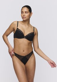 Conjunto de lencería negra que incluye un sujetador estructurado con malla acolchada y un detalle decorativo en forma de cuadrado, acompañado de un tanga a juego con un diseño de celosía.
