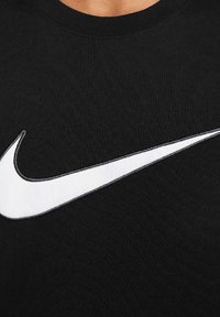 T-shirt in cotone nero con grande logo Nike swoosh bianco, girocollo e tessuto morbido con dettagli a costina.