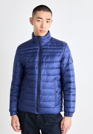 Chaqueta acolchada azul con un alto cuello, cierre de cremallera, patrón de acolchado horizontal, puños elásticos y dos bolsillos laterales con botón.