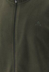 Chaqueta de forro polar verde con cuello alto, cremallera completa y un logo sutil. La textura es suave y la tela presenta una paleta de colores apagados.