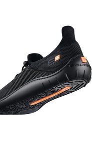 Czarne buty wsuwane z teksturowanym cholewką z materiału dzianinowego i pomarańczowymi akcentami. Posiadają gumową podeszwę z wzorzystym bieżnikiem dla lepszej przyczepności.