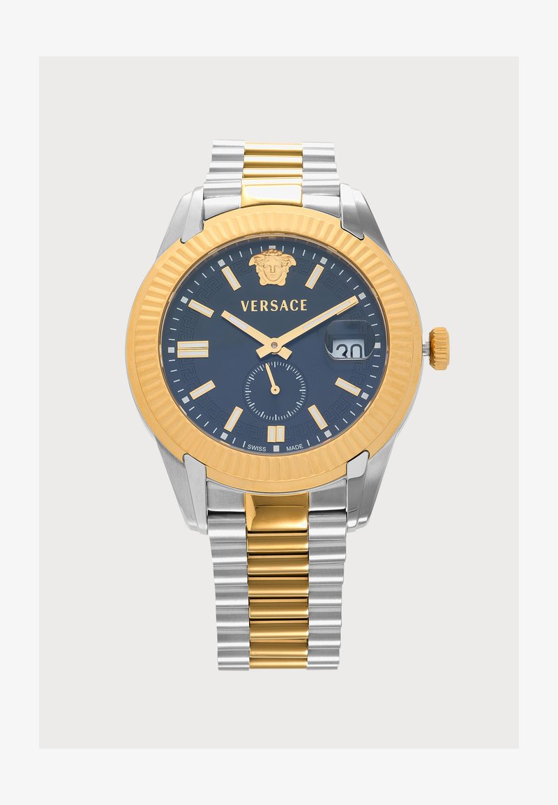 Montre-bracelet Versace avec bracelet en métal or et argent, cadran noir, index et aiguilles dorés, guichet date à trois heures et logo Méduse en haut.