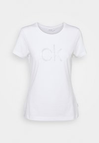 Vit kortärmad T-shirt i bomull, med en rhinestone "CK" logotyp i mitten. Klassisk rund halsringning, mjuk textur och normal passform.