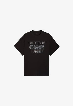 Czarny T-shirt Puma z krótkim rękawem z błyszczącym srebrnym napisem "PROPERTY OF LA FRANCE" i pękniętą owalną grafiką na środku.