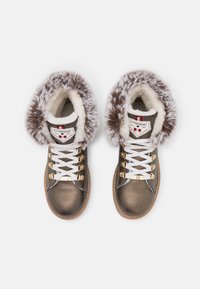 Botas altas de cuero marrón con cuello de piel sintética, cordones blancos, acentos metálicos y etiqueta con logo en la lengua. Punta redondeada y superficie texturizada.