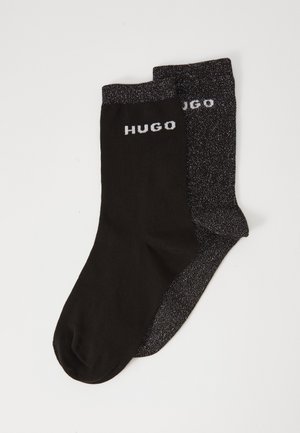 Chaussettes noires avec une paire de gris foncé contrastante, présentant une texture brillante et le logo "HUGO" en blanc sur le revers de chaque chaussette.