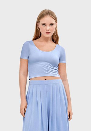 Top corto azul claro hecho de una tela suave y elástica con escote redondeado y mangas cortas, combinado con una falda plisada a juego.
