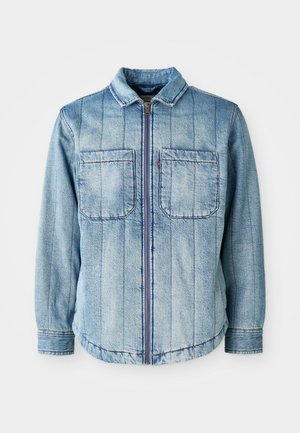 Lyseblå denimjakke med glidelås, to brystlommer og vertikale sømmer. Klassisk krage og elastisk kant.