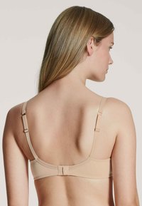 Reggiseno senza cuciture in tessuto liscio, con spalline regolabili e chiusura a gancio. Caratterizzato da un design semplice e da una silhouette elegante, adatto per l'uso quotidiano.