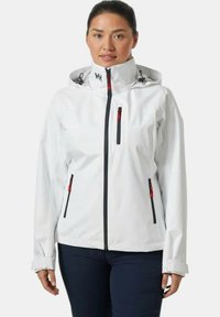 Chaqueta impermeable blanca con cremalleras negras, detalles en rojo y capucha ajustable. Presenta múltiples bolsillos y un diseño entallado.