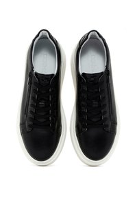 Sneaker in pelle nera con finitura liscia, suole in gomma bianca a contrasto, lacci tradizionali e dettaglio con zip laterale.