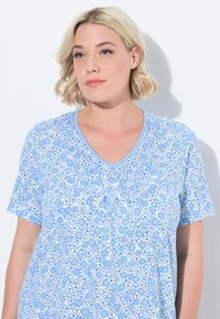 Top corto a maniche corte blu a V, realizzato in tessuto leggero. Il motivo presenta fiori blu chiaro e scuro con accenti gialli.