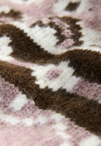 Wolltextil mit einem gemusterten Design in Nuancen von Pink, Weiß und Braun. Die Textur ist weich und flauschig und zeigt aufwendige Stiche.