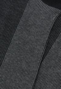 Stickad textil med två nyanser av grått: en ljus, något texturerad stickning, den andra mörkare och mer tätt vävd.