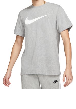 Personne portant un t-shirt Nike gris clair avec un grand logo blanc Swoosh et un short Nike gris assorti avec un logo noir.