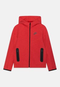 Czerwona bluza z kapturem na zamek z przodu, kontrastowymi czarnymi kieszeniami na zamek i kapturem. Posiada subtelną teksturę i logo Nike na piersi.