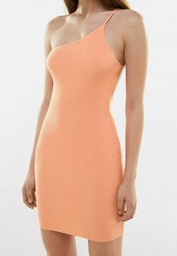 Robe côtelée à une épaule de couleur pêche. Matière ajustée et extensible avec une texture lisse. Ourlet se terminant au-dessus du milieu de la cuisse. Détails métalliques minimalistes.