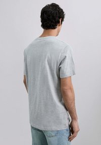 Camiseta gris de manga corta, hecha de tejido suave, con cuello redondo y un corte relajado, con detalles de costura visibles y un dobladillo recto.
