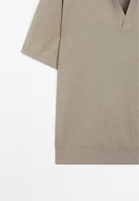 Khaki top s krátkým rukávem a výstřihem do V, vyrobený z texturované pleteniny s ribbed manžetami a lemem. Jednoduchý, moderní design bez vzorů.