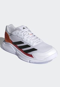 Witte sportschoen met mesh bovenwerk, zwarte strepen en oranje accenten. Ronde neus, gestructureerde zool en gewatteerde kraag voor ondersteuning.