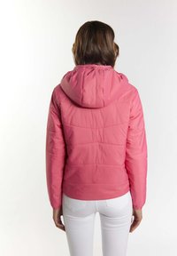 Giacca a vento rosa con cappuccio, caratterizzata da cuciture orizzontali e polsini elastici. Indossata con jeans bianchi. Texture liscia, design casual.