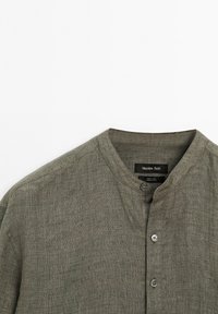 Olive green linen shirt with a round neckline and three buttons, featuring the Massimo Dutti brand label displayed prominently.
