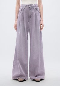 Τζιν φαρδιά στο κάτω μέρος σε ανοιχτό λεβαντί χρώμα, με ψηλή μέση, πιέτες και κλασικό κούμπωμα με κουμπιά. Λείο, απαλό ύφασμα με ελάχιστη ξεθώριαση.