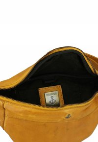 Borsa in pelle gialla con chiusura a zip. Fodera in tessuto nera, etichetta metallica "HARBOUR" all'interno e un emblema di ancora all'esterno.