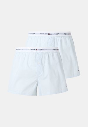 Dwie białe bawełniane bokserki z cienkimi pionowymi paskami i elastycznymi pasami z logo i marką Tommy Hilfiger.