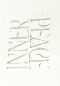 Tissu blanc avec un texte métallique argenté portant la mention « TROUVEZ VOTRE PAIX INTÉRIEURE » en grandes lettres stylisées et verticales avec une texture douce.