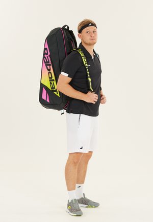 Sort sport rygsæk med pink og gul gradientdetaljer. Inkluderer justerbare stropper og et rummeligt design. Modellen har en sort polo og hvide shorts på.