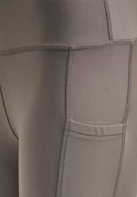 Tætsiddende grå leggings lavet af strækbart stof, med en sidelomme og tekstureret syning langs sømmene.